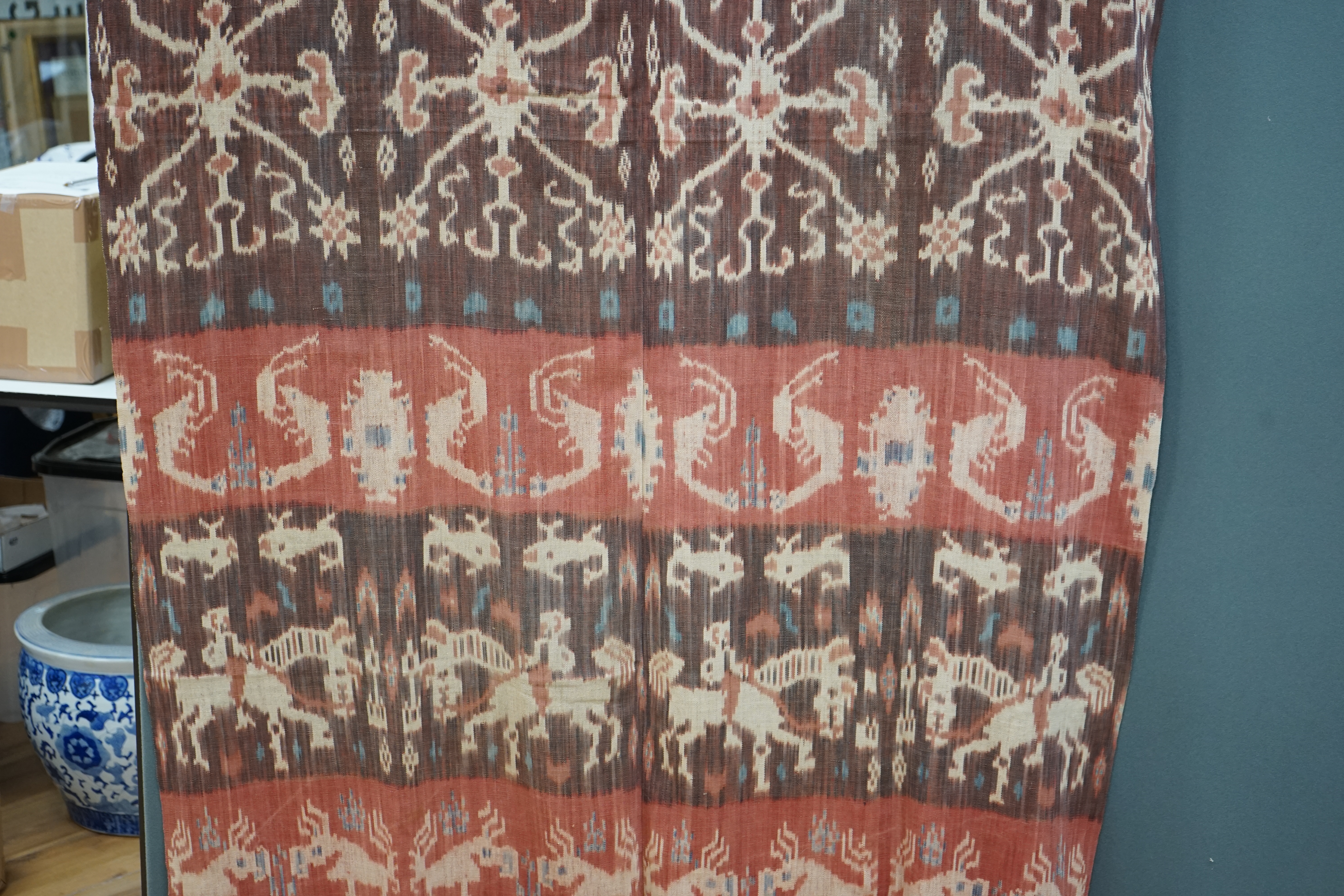 A hand woven hand dyed Ikat Sumbanese Hinggi (shoulder cloth), together with an Indian chain stitch embroidered panel, the Hinggi woven on two short 56cm wide looms sewn together forming horizontal bands, depicting men o